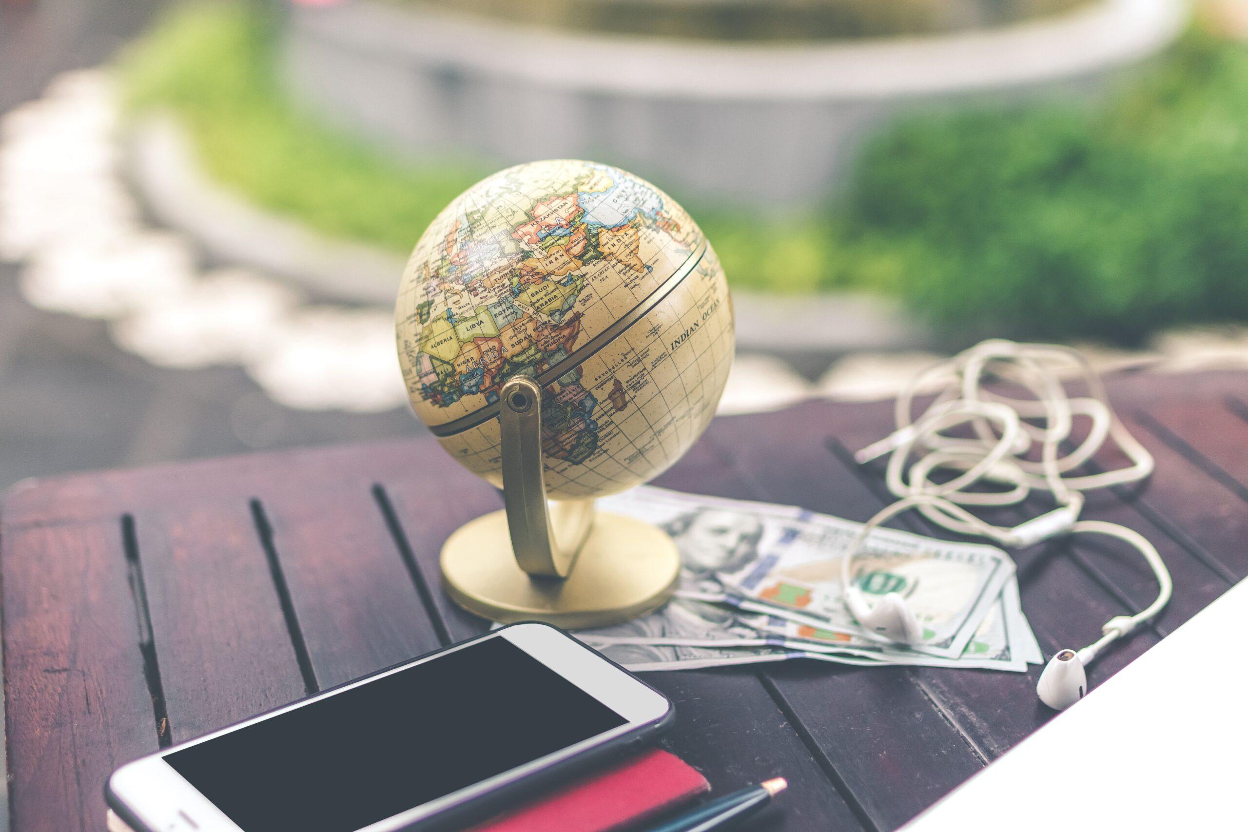 A globe and a smartphone placed on a table, illustrating tips for traveling with a smartphone.